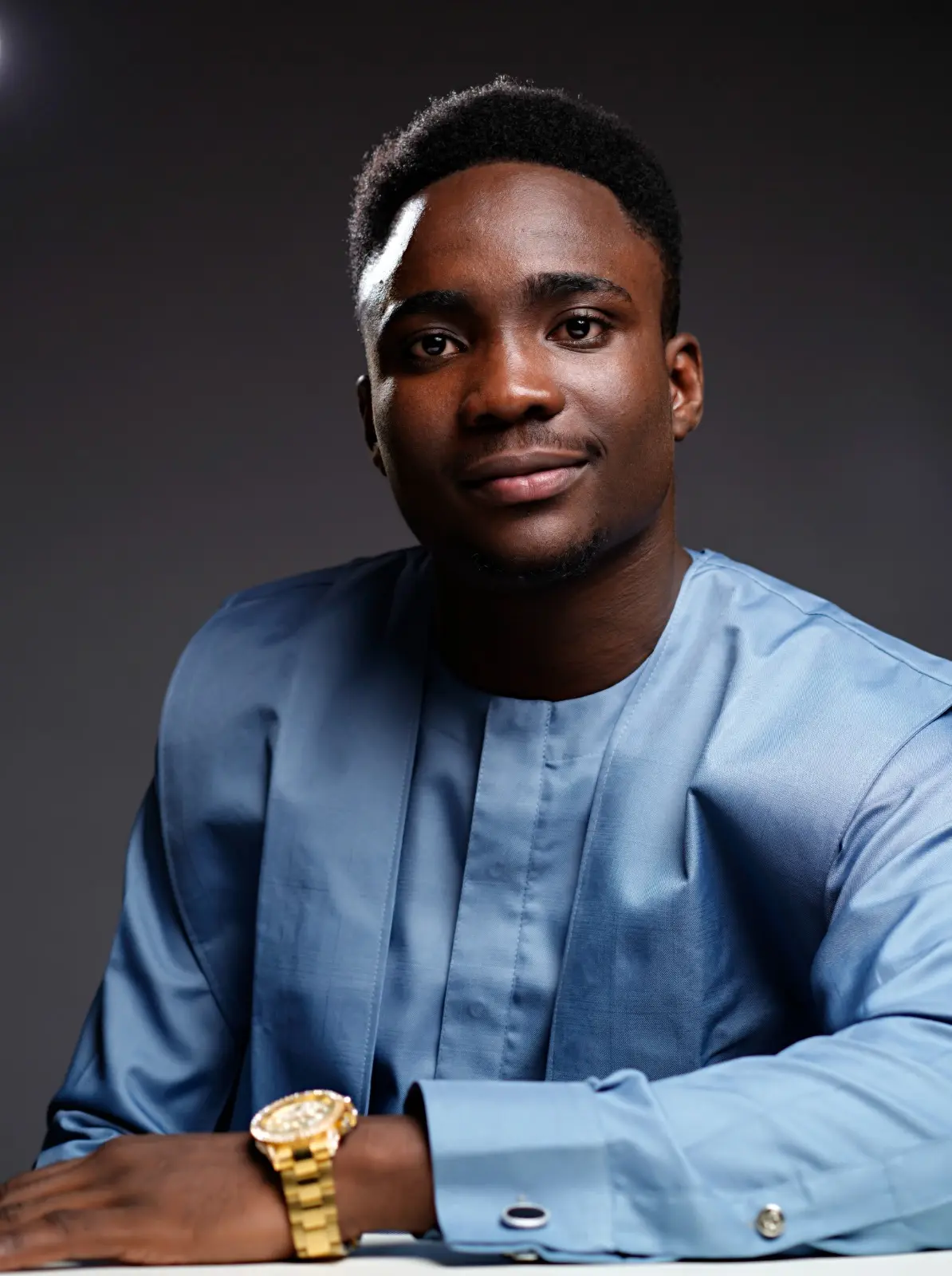 Oluwaferanmi Iyiola in a blue kaftan at a studio desk